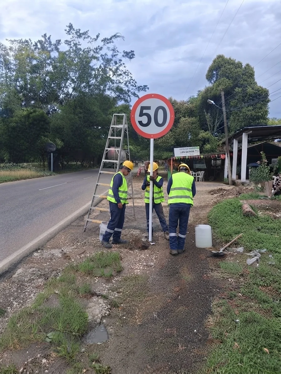 Tres trabajadores instalando señal de tránsito en vía pública